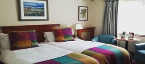 A hotel room with two beds, a chair, a small table, and a window with curtains. - Parkway Hotel and Spa (Cwmbran)