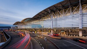 A modern airport terminal with a large glass facade, multiple entry points, and a curved roof structure. - Charming 3-bedroom Guest house in enchanting San Jose with AC (San Jose)