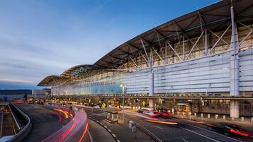 Una moderna terminal de aeropuerto con una amplia fachada de vidrio, múltiples accesos y una estructura de techo curva.