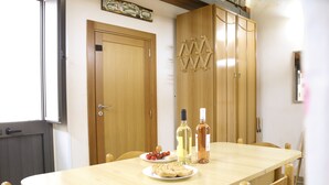 A dining area with a wooden table, chairs, and a cabinet with hooks. There are two bottles on the table. - Two-story La Volta Court (Tuglie)