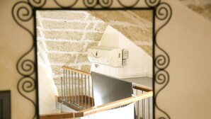 A mirror reflecting a staircase with a stone wall and a whiteboard. - Two-story La Volta Court (Tuglie)
