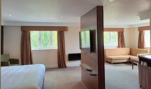 Une chambre d’hôtel avec un lit, un canapé, une télévision et un bureau.