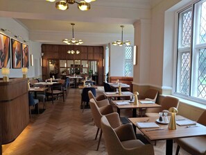 A restaurant interior with wooden flooring, multiple tables, chairs, and pendant lighting. - Letchworth Hall (Letchworth)