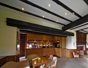 A dining area with wooden furniture, a bar with bottles, and exposed beams on the ceiling. - Letchworth Hall (Letchworth)