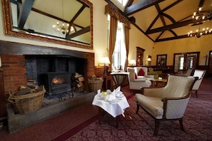 A cozy room with a fireplace, comfortable seating, and a large mirror. - Letchworth Hall (Letchworth)