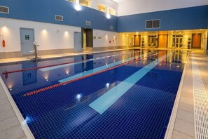An indoor swimming pool with clear lanes, a blue tiled floor, and a tiled wall. - Letchworth Hall (Letchworth)