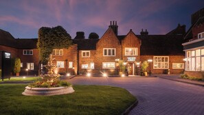 A brick building with a pub named 'VOCO' at the entrance, a paved driveway, and a landscaped garden with a fountain. - Letchworth Hall (Letchworth)