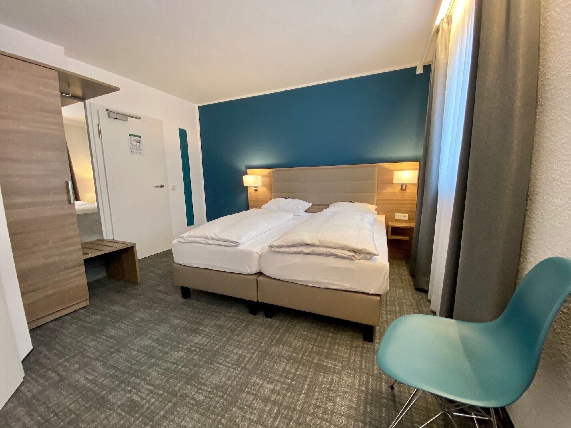 Ein Hotelzimmer mit Bett, Schreibtisch, Stuhl und Kleiderschrank.