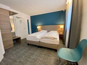 A hotel room with a bed, a desk, a chair, and a wardrobe. - Comfort Garni Hotel (Bielefeld)