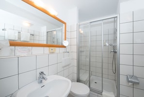 A modern bathroom with a glass-enclosed shower, a sink, and a toilet. - Comfort Garni Hotel (Bielefeld)