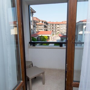 A balcony with a view of multi-story buildings, a small table, and a chair. - Nevis Resort & Aqua Park - All Inclusive (Nessebar)
