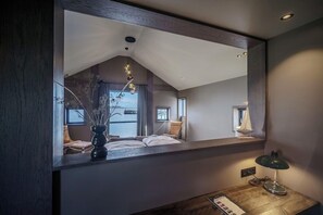 Una camera da letto con un grande specchio, un comodino, una lampada e vista sull'interno della stanza.