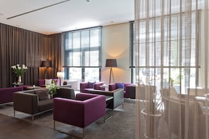 A modern hotel lobby with multiple seating areas, large windows, and a decorative plant arrangement. - Hotel 47 (Konstanz)