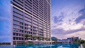 A modern hotel with a large pool, multiple floors, and a clear view of the surrounding landscape. - Genpla Hotel Shenzhen Nanshan (Shenzhen)