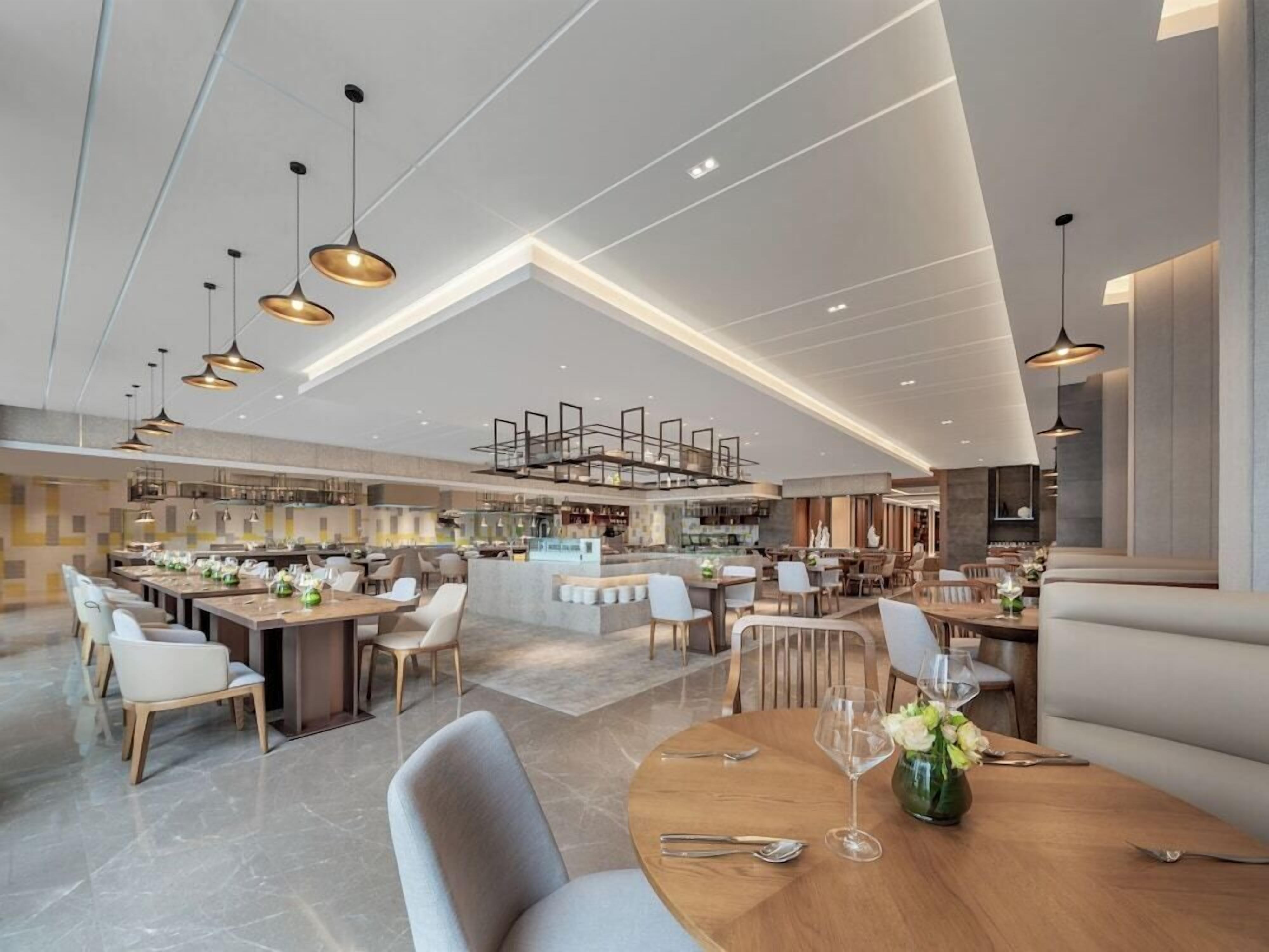 A spacious, modern restaurant with high ceilings and contemporary lighting fixtures.