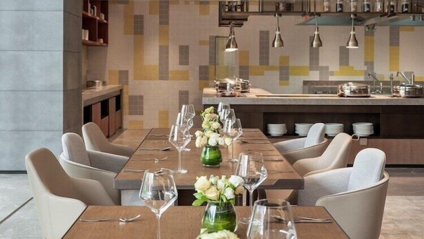 A modern dining area with a long table set for a meal, surrounded by chairs. - Genpla Hotel Shenzhen Nanshan (Shenzhen)