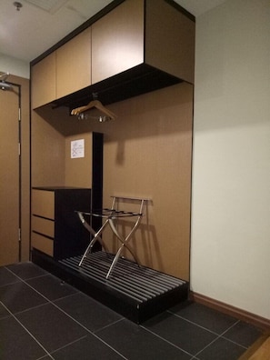 A hotel room with a built-in wardrobe, a black metal drying rack, and a tiled floor. - Roxy Hotel Apartment (Kuching)