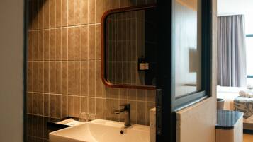 A bathroom with a white sink, a mirror, and a window.
