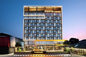 A modern hotel with a prominent 'PORTA' sign, featuring a grid-like facade and a well-lit entrance. - Porta by The Ambarrukmo (Depok)
