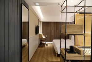 A hotel room with a bed, a desk, a chair, a mirror, and a window. - Porta by The Ambarrukmo (Depok)