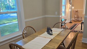 Un espace repas comprenant une longue table en bois, six chaises en bois et un chemin de table décoratif.