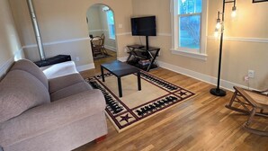 Un salon doté d’un ventilateur de plafond, d’un téléviseur, d’une cheminée et d’une grande fenêtre.