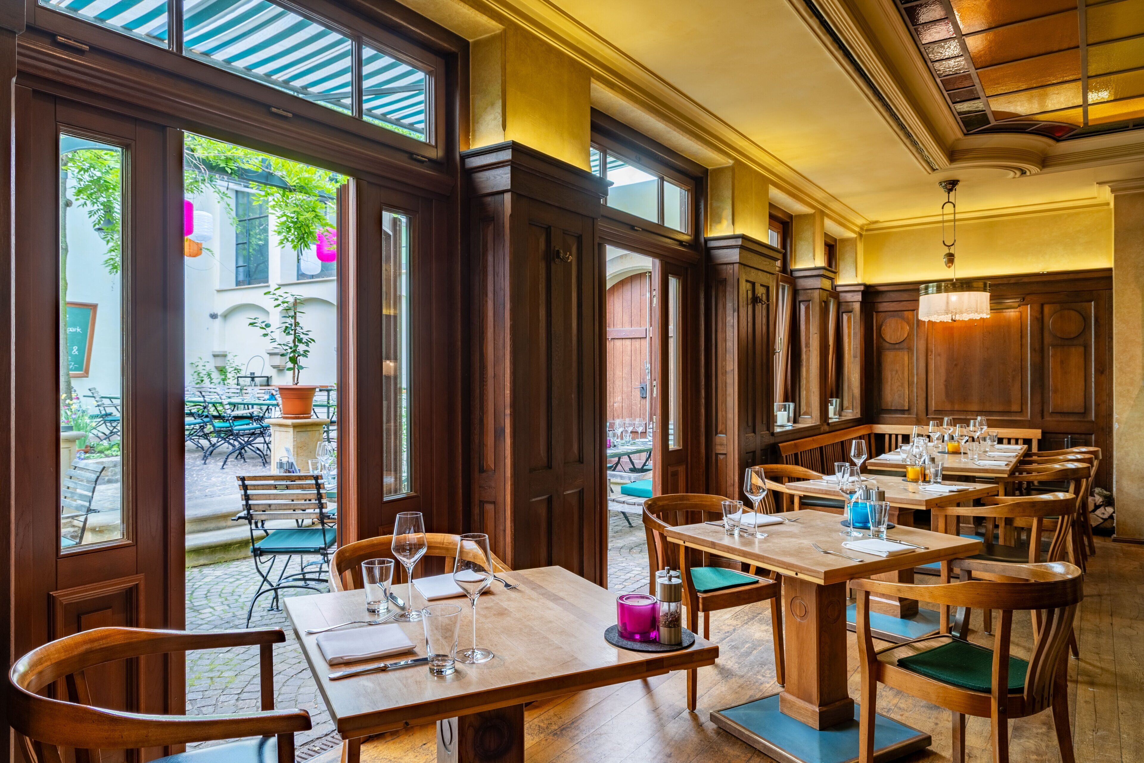 Ein Restaurant mit Holztischen und -stühlen, großen Fenstern und Blick auf die Straße.