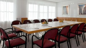 A conference room with a long table, red chairs, white curtains, and ceiling lights. - Hotel Zumnorde (Erfurt)