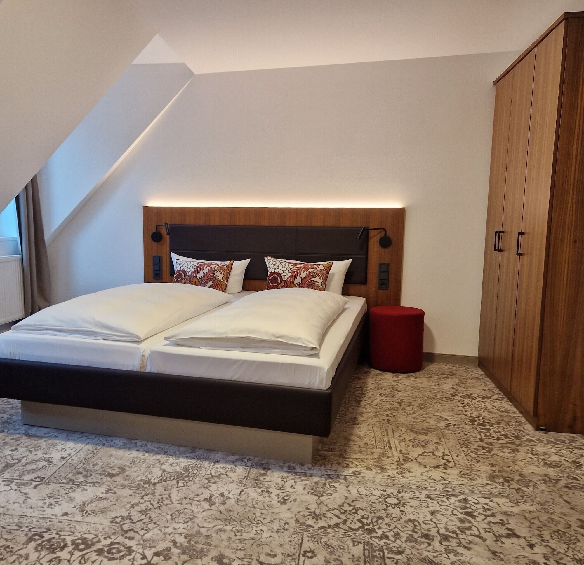 Ein Schlafzimmer mit einem großen Bett, einem Holzschrank und einem roten Hocker.