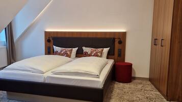 Ein Schlafzimmer mit einem großen Bett, einem Holzschrank und einem roten Hocker.