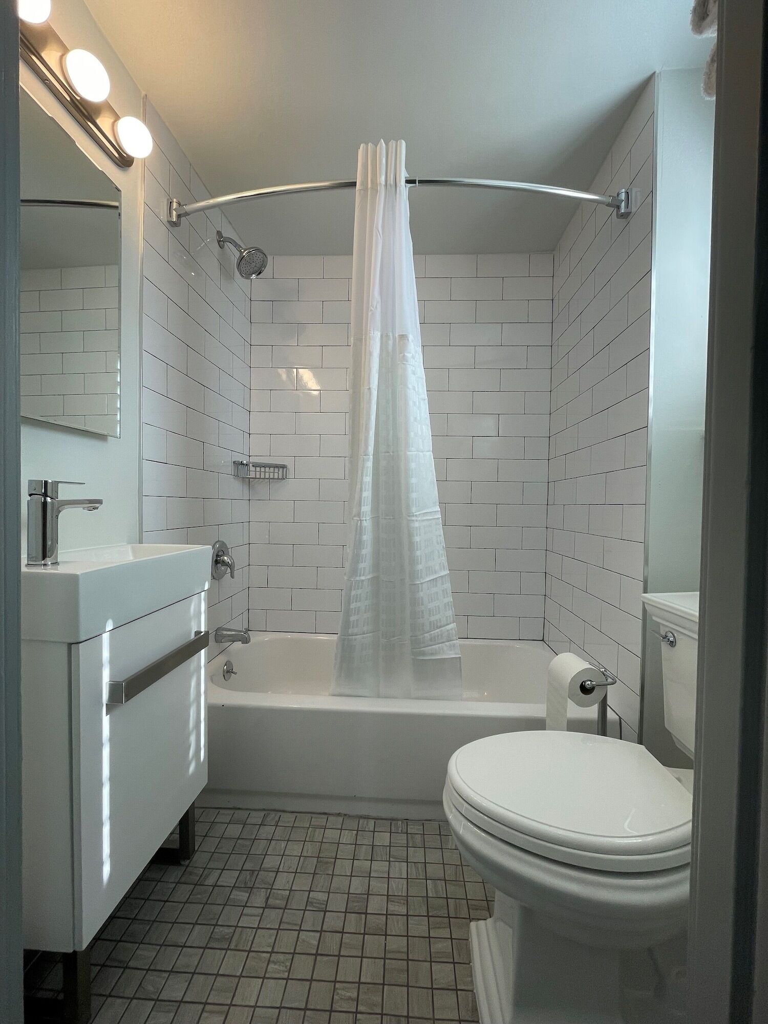 A modern bathroom with a bathtub, toilet, and vanity.