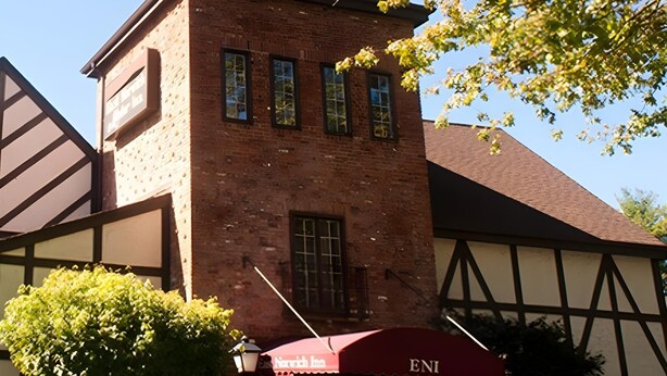 Ein Backsteinhaus mit vielen Fenstern und einem roten Vordach, auf dem 'ENI' steht.