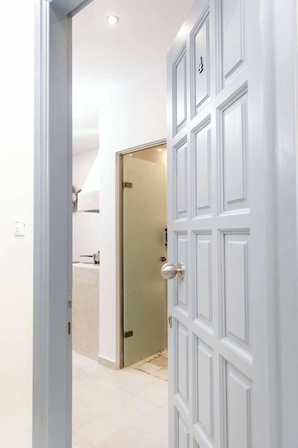Ein Flur mit einer weißen Tür, die zu einem Badezimmer führt.