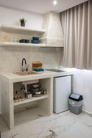 Een kleine keuken met een spoelbak, aanrecht en opbergplanken.