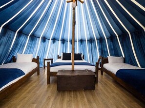 A tent-style room with three beds, a central table, and a hanging light fixture. - Warwick Castle (Warwick)