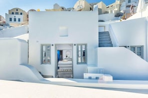 A modern white building with a staircase leading to a balcony, surrounded by similar structures. - Diamond Luxury Suites (Santorini)