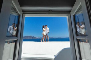 A room with a large window overlooking a scenic view. - Diamond Luxury Suites (Santorini)