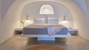 Une chambre à coucher moderne avec un lit suspendu, des murs blancs et un plafond en arc unique.