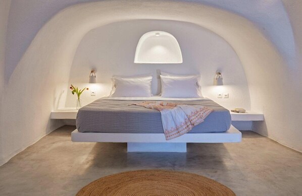 A modern bedroom with a floating bed, white walls, and a unique arched ceiling. - Diamond Luxury Suites (Santorini)