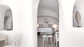 A minimalist interior with white arches and a central seating area. - Diamond Luxury Suites (Santorini)