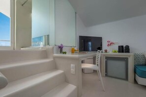 A modern, minimalist room with a white staircase, a flat-screen TV, and a small seating area with a cushion. - Diamond Luxury Suites (Santorini)