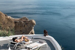 En person som kopplar av på en solstol med utsikt över havet och klippiga branter.
