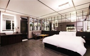 A modern hotel room with a large bed, a vanity with a mirror, a seating area, and a view of the outdoors. - Le Idea Hotel (Pohang)