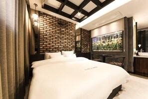 A modern hotel room with a large bed, a brick accent wall, a dining area with a view, and a large window with flowers. - Le Idea Hotel (Pohang)