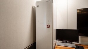 A white refrigerator with a control panel, a computer monitor, keyboard, and mouse on a wooden desk. - Le Idea Hotel (Pohang)