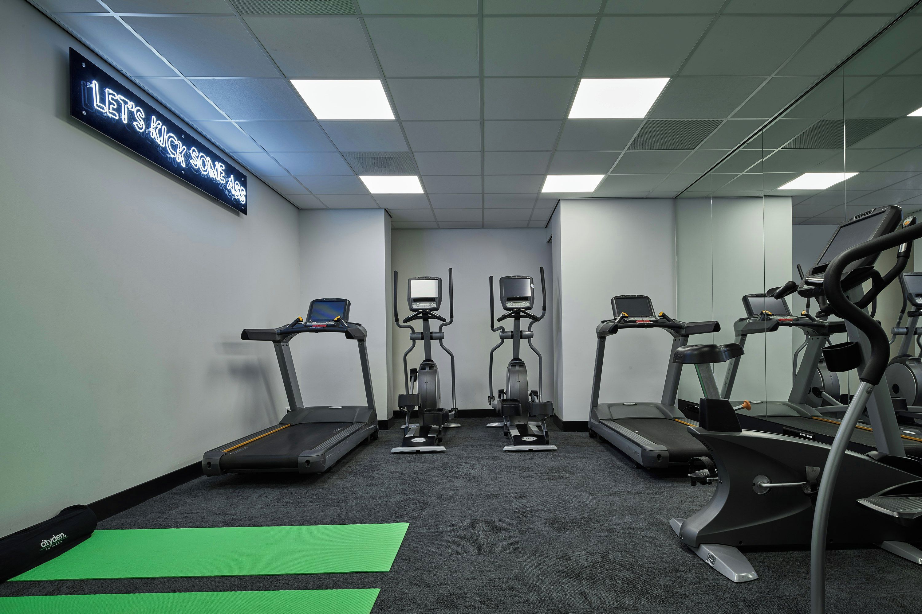 Ein Fitnessraum mit Laufbändern, Crosstrainern und stationären Fahrrädern.