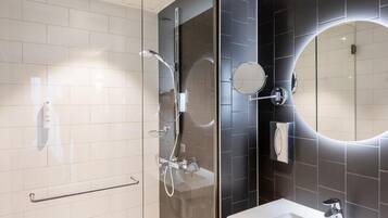Ein modernes Badezimmer mit einer gläsernen Duschkabine, einem weißen Waschbecken und einem großen Spiegel.