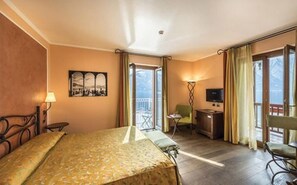 A hotel room with a bed, a desk, a chair, a television, and a balcony with curtains. - Hotel La Darsena (Tremezzina)