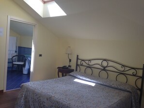 A bedroom with a bed, a nightstand, a lamp, a chair, and a skylight. - Hotel La Darsena (Tremezzina)