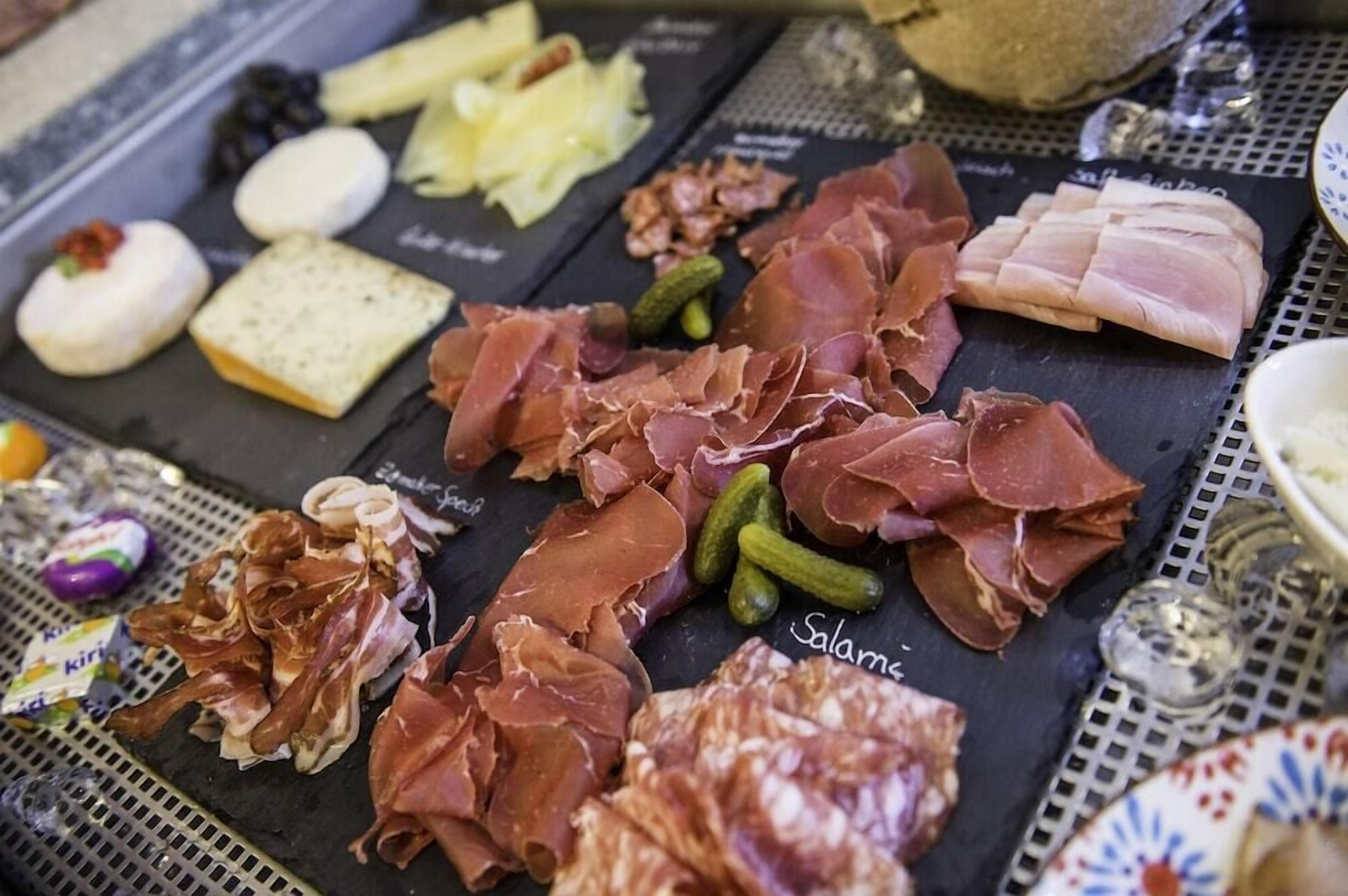 A charcuterie board with various meats, cheeses, and pickles.